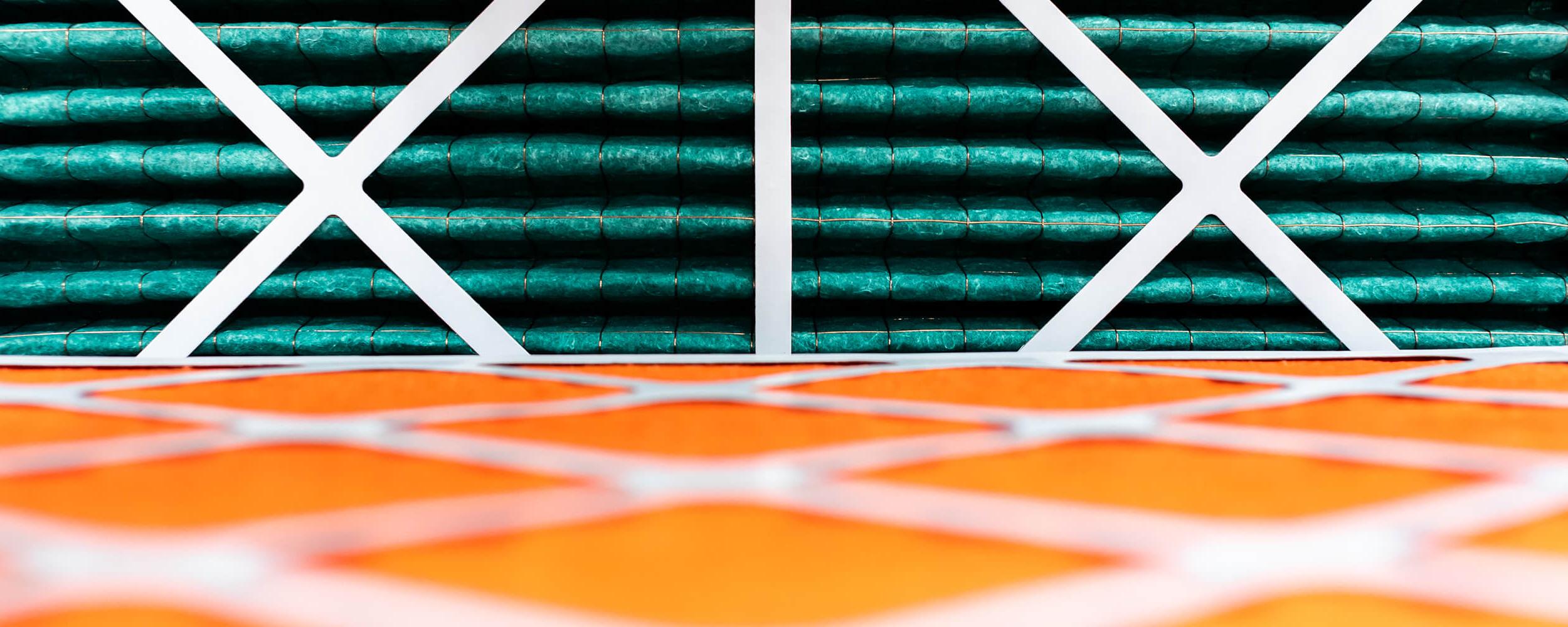 Close-up photography of rolls of orange and green insulating material being held in place with white cross frames